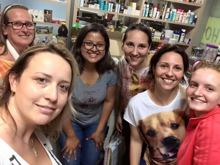 Equipe do Recanto dos Bichos reunida dentro da clínica veterinária, com um cão no colo.