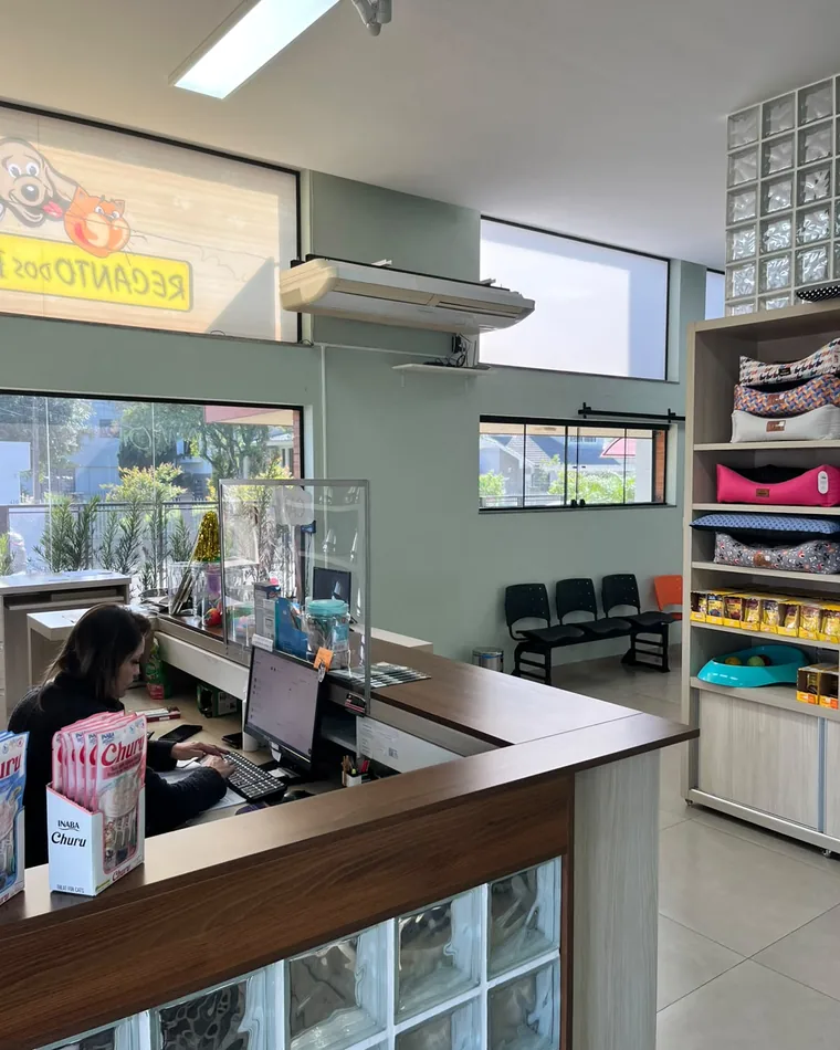 Recepção da clínica veterinária Recanto dos Bichos, com atendente no balcão e a sala de espera ao fundo.