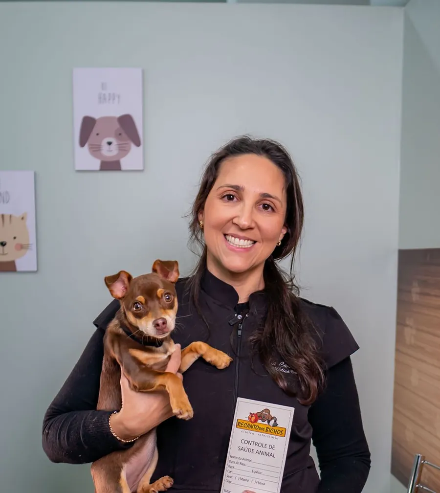 Médica veterinária do Recanto dos Bichos segurando um cão de pequeno porte no colo.